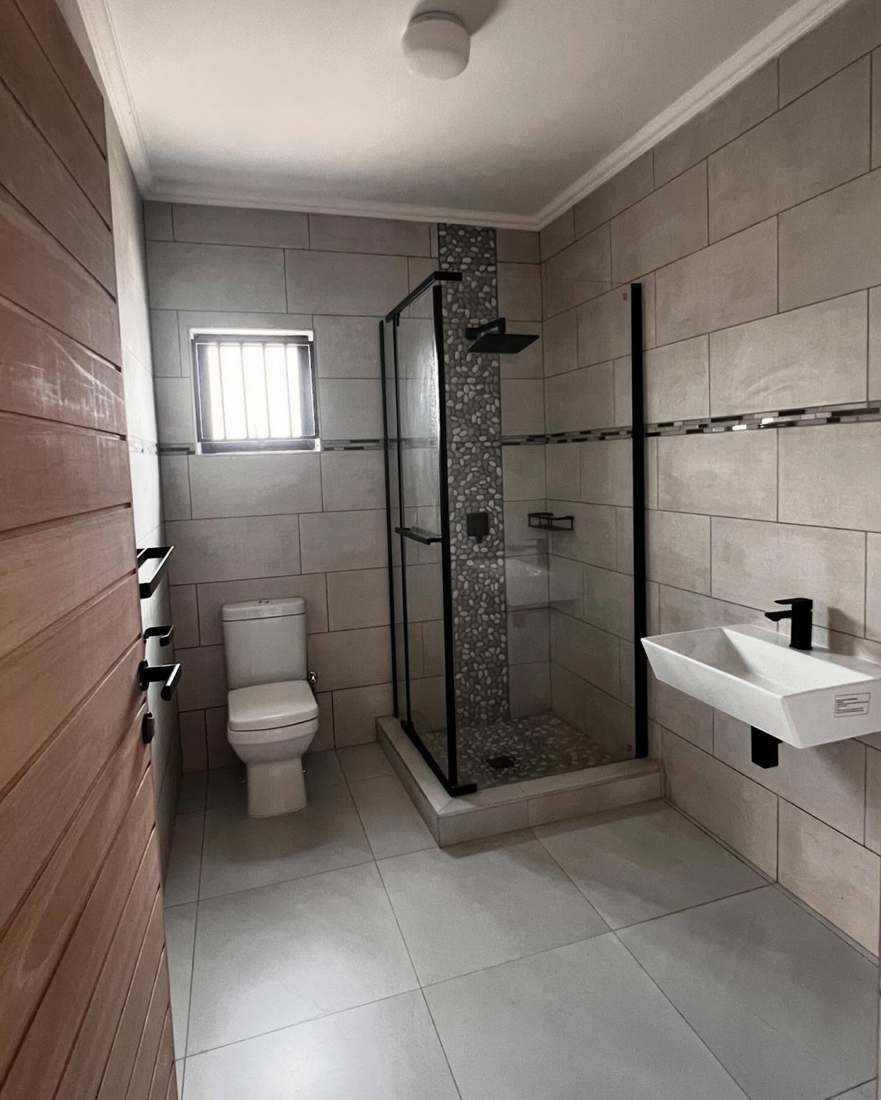 Fully tiled bathroom with glass shower, sanitaryware, and finishes installed