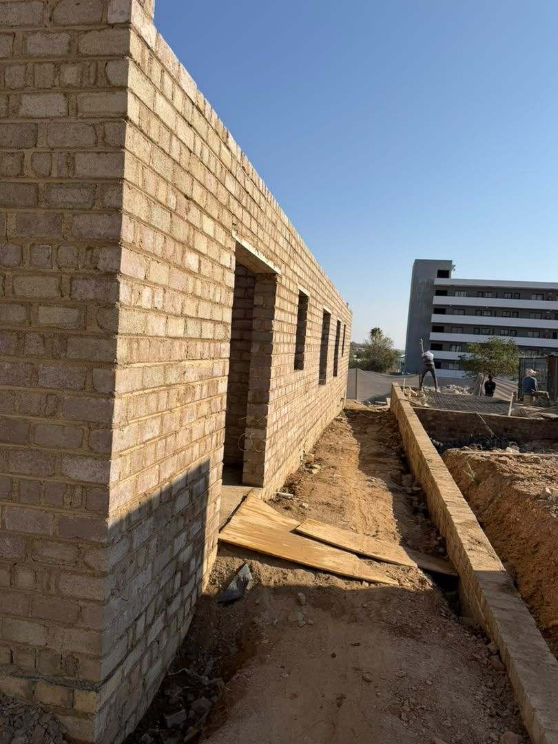 Service trench and strip footing cut alongside a rising blockwork wall
